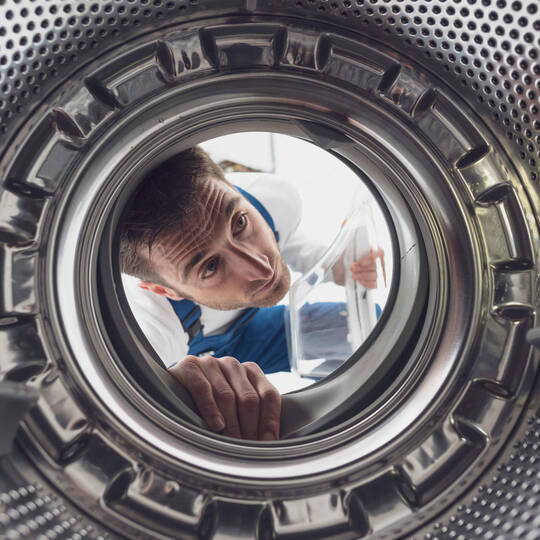 Ein Mann schaut in die Waschmaschine. 