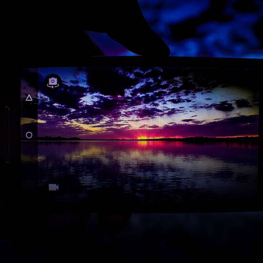 Sonnenuntergang auf Smartphonedisplay durch Kamera