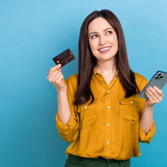 Frau hält Smartphone und Kreditkarte in die Luft