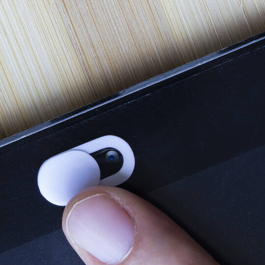 Finger zeigt auf die Frontkamera eines schwarzen Smartphones.