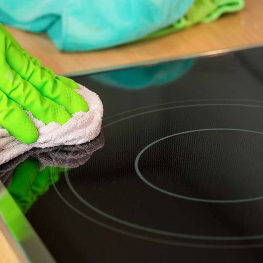 Person wischt mit einem Lappen über ein Ceranfeld