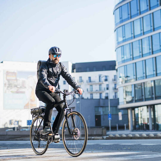 Mann mit Helm fährt auf E-Bike.