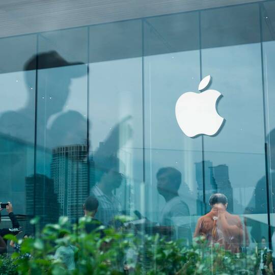 Leute, welche das Apple-Logo an einer Glasfront Photographieren