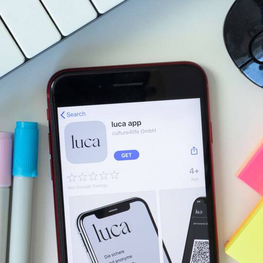 Smartphone mit Luca App auf Schreibtisch
