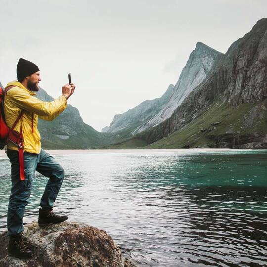 Wanderer macht Fotos mit seiner Smartphone-Kamera von der Landschaft