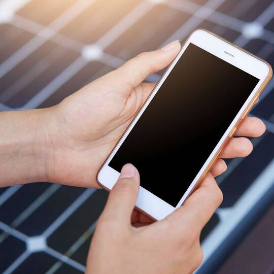 Smartphone vor einer Solarzelle