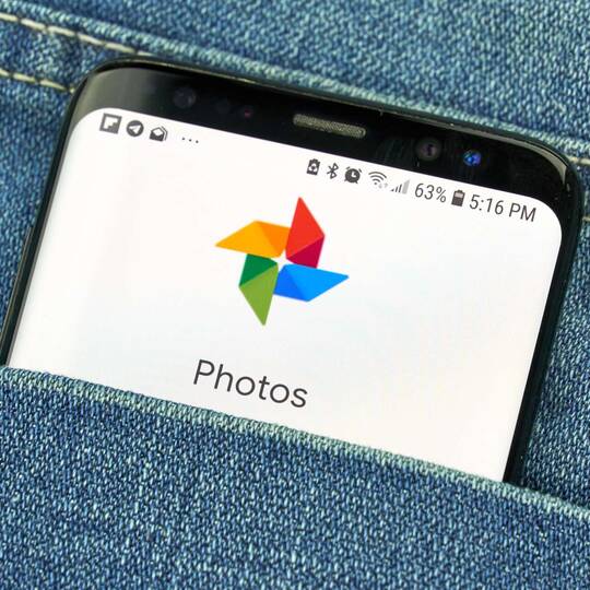 ein Smartphone steckt in der Hosentasche und zeigt dei Google Fotos App