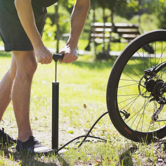 Eine Person pumpt den Reifen eines Fahrrads auf.