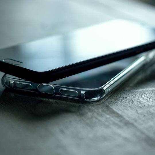 Schmarzes Smartphone liegt auf einer transparenten Hülle