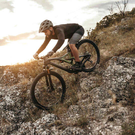 Mann fährt Mountainbike steilen Berg hinunter.