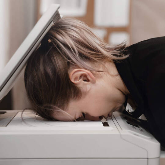 Frau legt Kopf in Drucker und ist verzweifelt