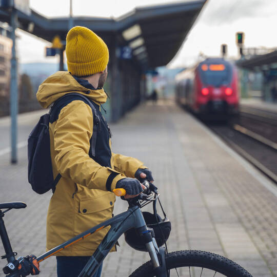Ein Mann wartet mit seinem Fahrrad auf dem Zug