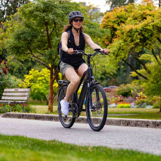 Frau auf Fahrrad fährt durch Park.