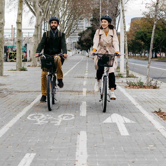 Zwei Personen fahren nebeneinander auf Fahrrädern über einen Radweg.