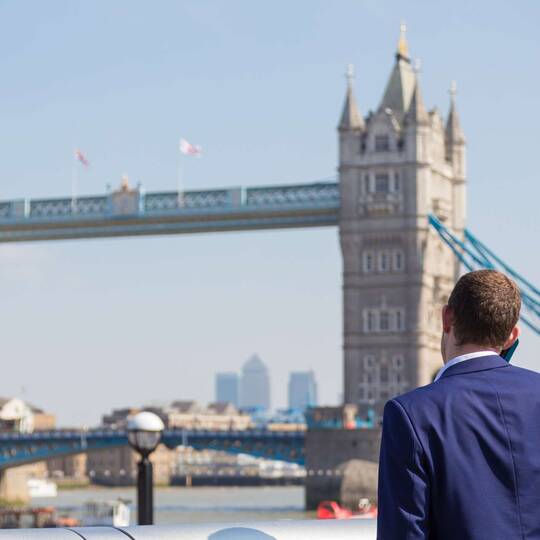 Mann steht vor London Bridge und telefoniert