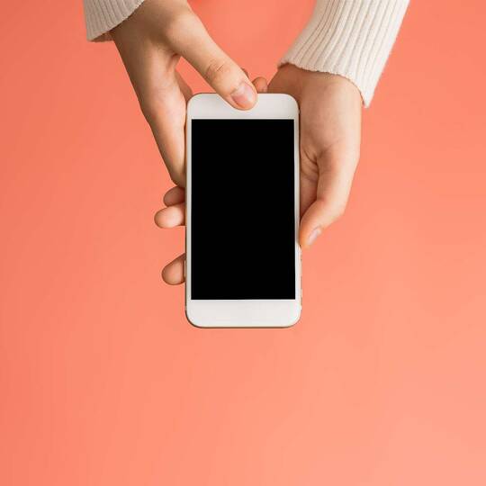 Person hält iPhone mit schwarzem Display in den Händen