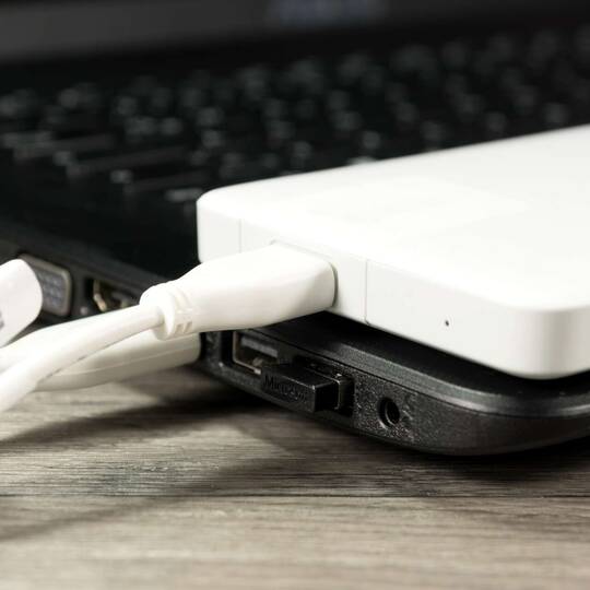 Externe Festplatte liegt angeschlossen auf Laptop