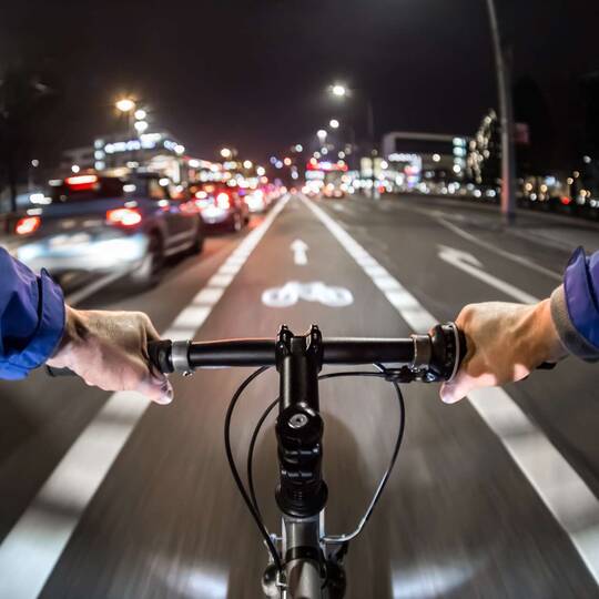 Radfahrer bei Dunkelheit im Stadtverkehr auf Fahrradweg
