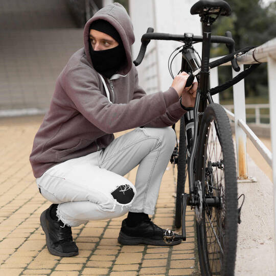 maskierter Mann klaut angeschlossenes Fahrrad