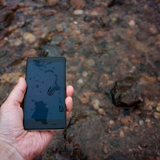 Hand hält Smartphone in den Regen