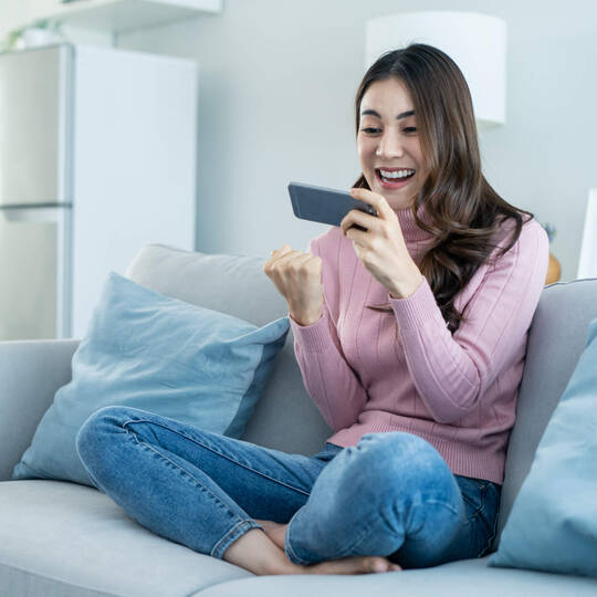 Frau sitzt auf Sofa mit Smartphone