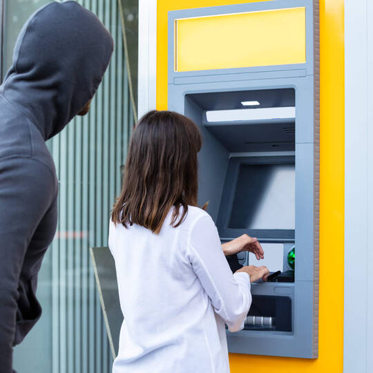 Mann beobachtet PIN Eingabe am Bankautomaten