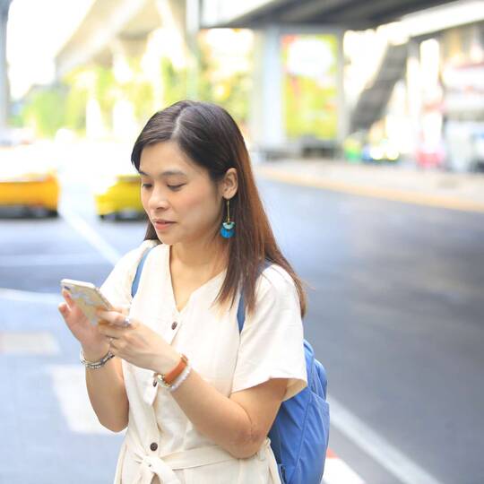 Frau schaut auf Smartphone an öffentlichem Ort