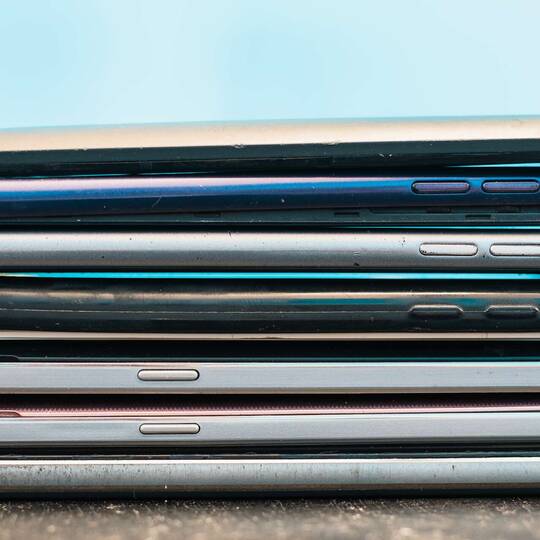 Viele Smartphones liegen aufeinander vor blauem Hintergrund