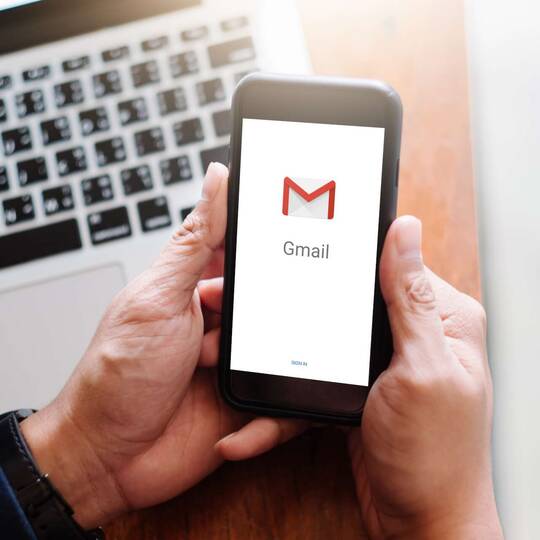 Smartphone mit geöffneter Gmail Applikation vor Macbook Tastatur