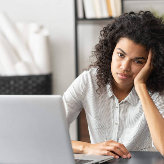 Eine Frau schaut frustiert auf ihren Laptop
