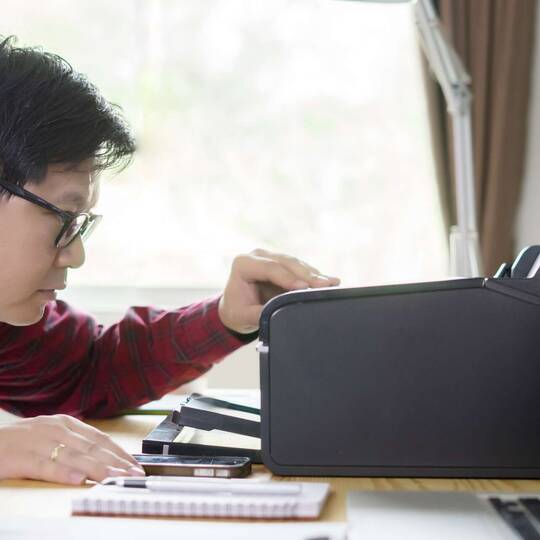 Person bedient schwrzen Drucker auf Arbeitstisch