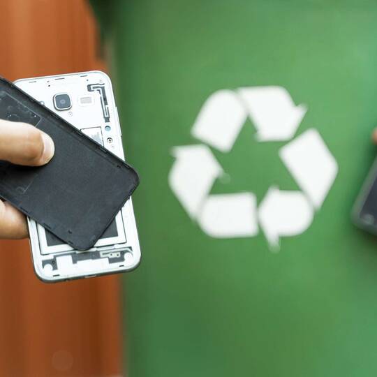 Handyteile vor Recycling-Symbol