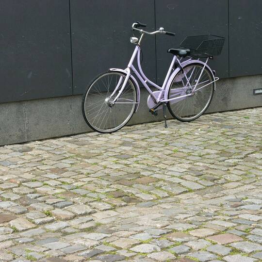 Das Hollandrad steht draußen vor einer Wand.