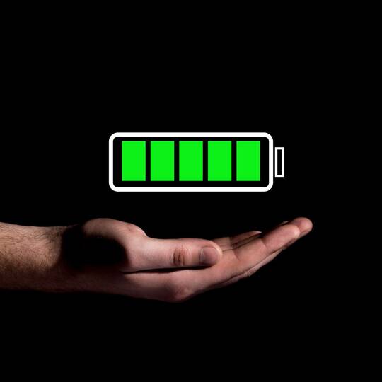 Volles Batteriesymbol schwebt über offener Hand