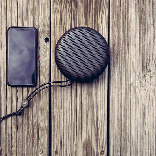 iPhone liegt auf Holzbrettern neben Lautsprecher