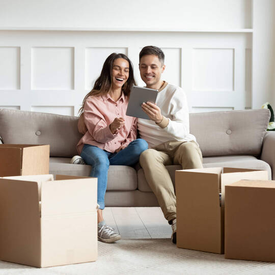 Frau und Mann sitzen auf Sofa und richten Wohnung ein