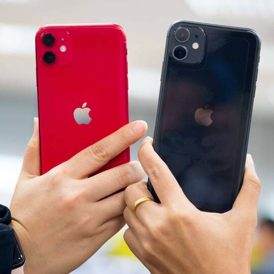 ein schwarzes und ein rotes iPhone werden nebeneinander gehalten