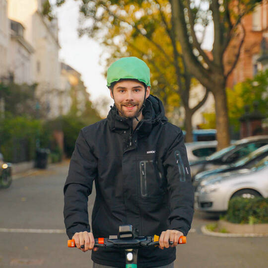 Mann auf E-Scooter fährt mit Inflabi Helm.