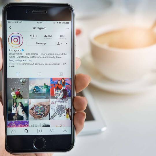 Smartphone wird in der Hand gehalten mit geöffneter Instagram App