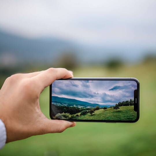 jemand fotografiert mit einem iPhone eine Landschaft