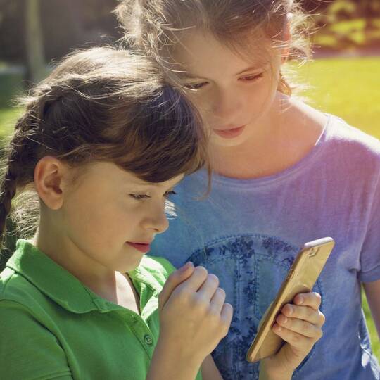 zwei Kinder gucken auf ein iPhone