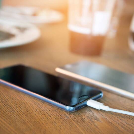 iPhoneliegt auf dem Tisch und lädt an einer Powerbank