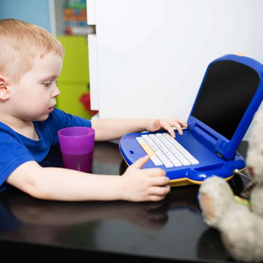 Ein kleiner Junge sitzt vor einem Kinder-Computer