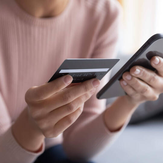 Frau tippt Kreditkartendaten in Handy ein