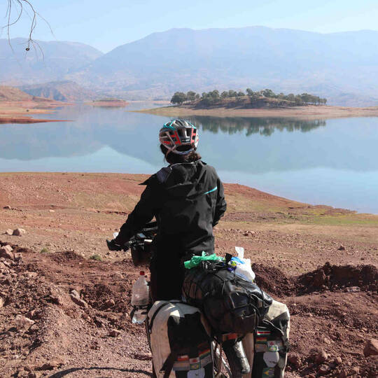 Frau fährt mit Fahrrad durch Landschaft in Marokko.