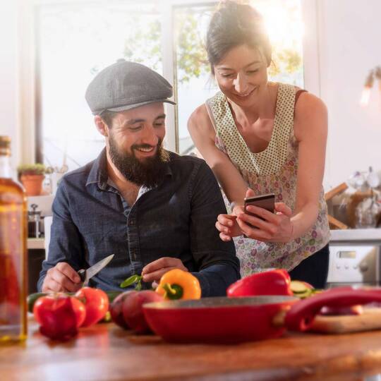 zwei Personen sitzen an einem Tisch und eine Frau zeigt etwas auf ihrem Smartphone