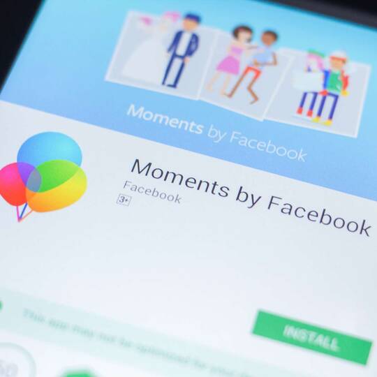 Smartphone, auf welchem "Moments" von Facebook angezeigt wird
