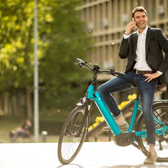 Mann steht mit seinem Fahrrad in der Stadt