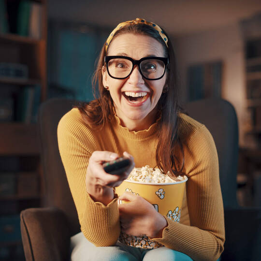 Frau schaut gespannt einen Film mit Popcorn in der Hand