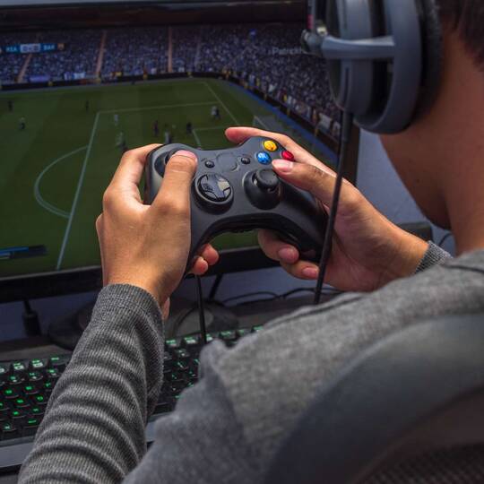 Mann mit Kopfhörern spielt Fifa auf einer Spielkonsole